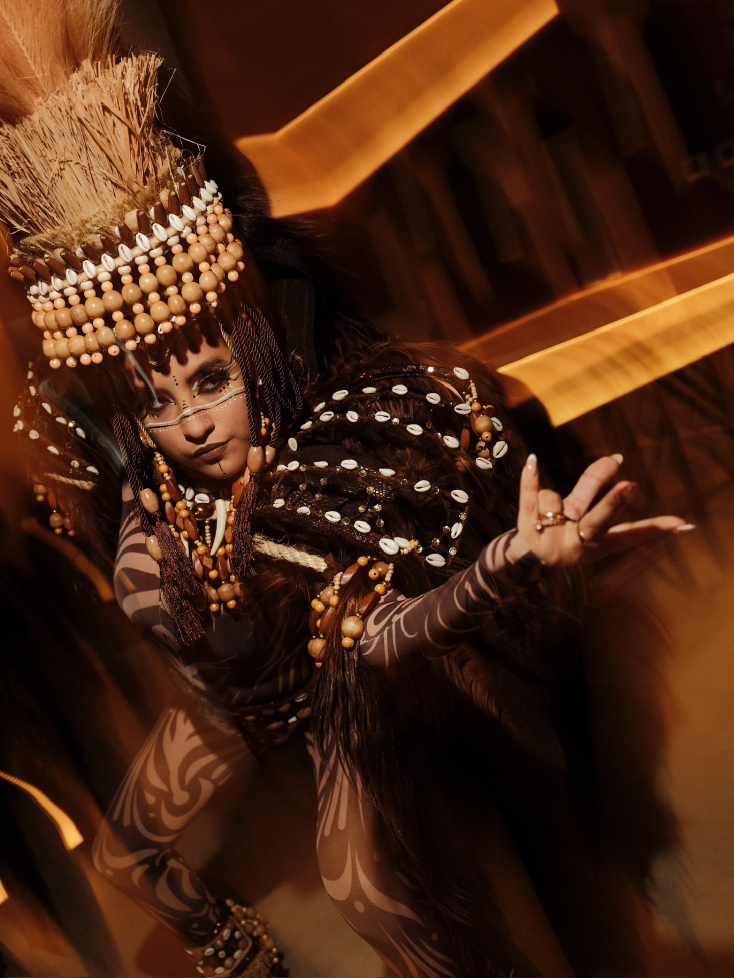 Dancer in a beaded tribal costume with shell and feather details in warm amber light